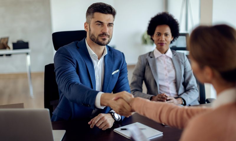 Businessman handshaking with potential candidate during a job interview in the office.